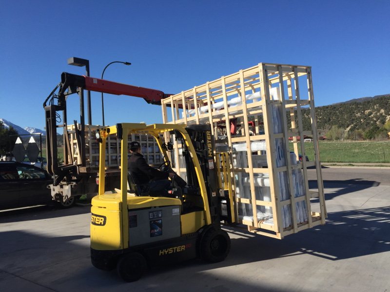 Forklift moving crated building materials for delivery