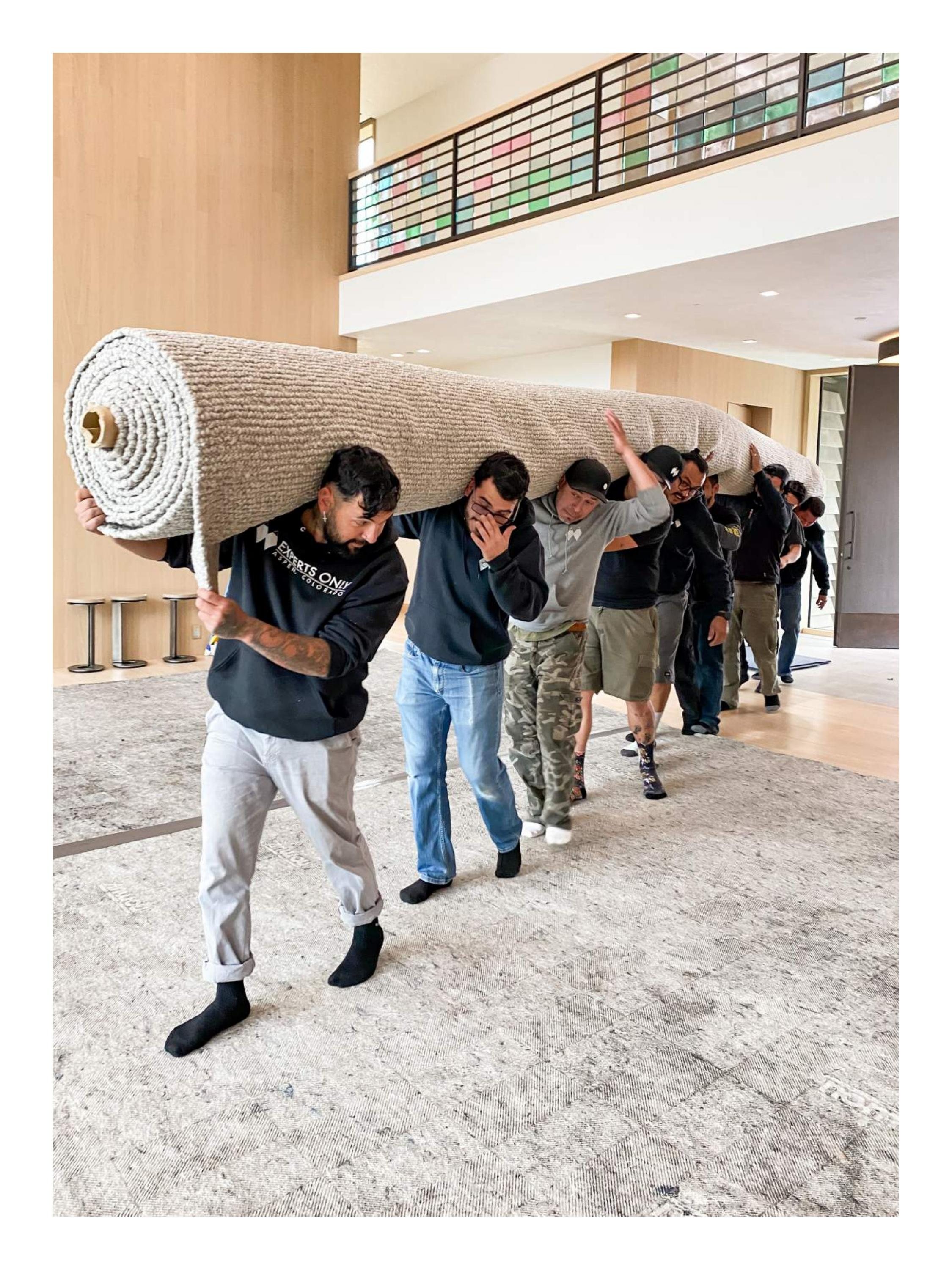 Double Diamond installation crew carrying a large rug through a finished home