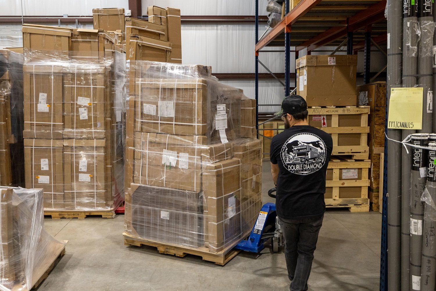 Warehouse team member moving staged materials with a pallet jack